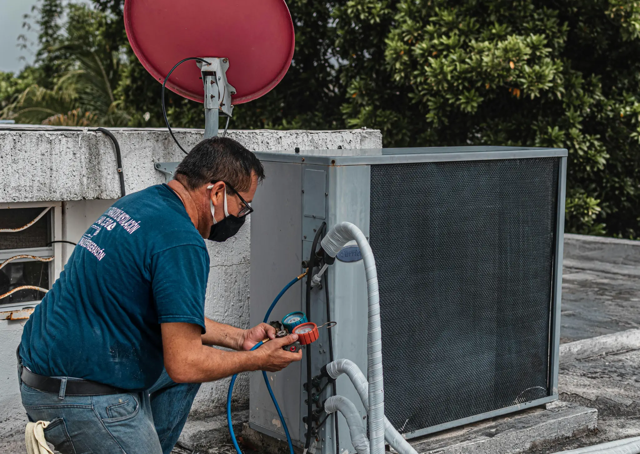 HVAC technician working on rooftop AC unit with tools